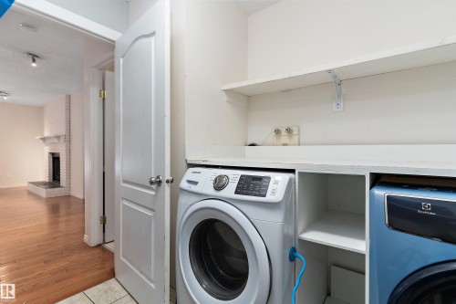 Laundry room with a brick fireplace and light wood-style flooring - 115 Walker Road, Edmonton, AB - Indoor Photo Showing Laundry Room