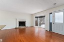 Unfurnished living room featuring wood-type flooring, a textured ceiling, and a tiled fireplace - 115 Walker Road, Edmonton, AB  - Indoor Photo Showing Living Room With Fireplace 