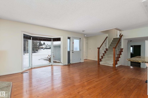 Unfurnished living room featuring light wood-style floors, healthy amount of natural light, and a textured ceiling - 115 Walker Road, Edmonton, AB - Indoor Photo Showing Other Room
