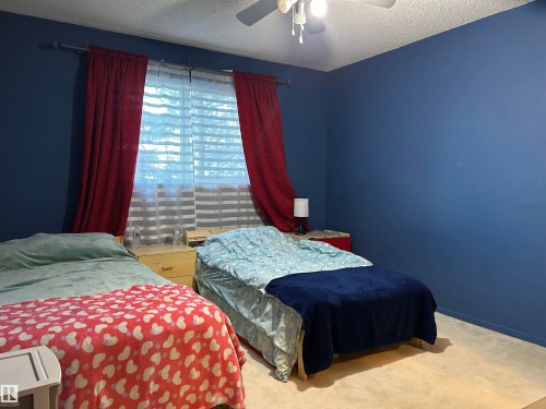 Bedroom featuring a textured ceiling, carpet floors, and a ceiling fan - 310 2430 Guardian Road, Edmonton, AB - Indoor Photo Showing Bedroom