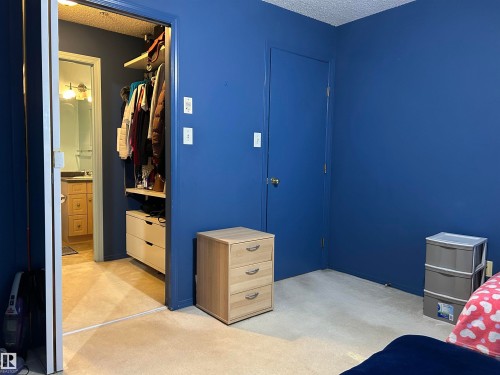 Bedroom with a textured ceiling, a closet, and light carpet - 310 2430 Guardian Road, Edmonton, AB - Indoor