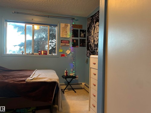 Bedroom featuring a textured ceiling and a baseboard radiator - 310 2430 Guardian Road, Edmonton, AB - Indoor Photo Showing Other Room