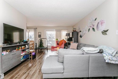 Living area featuring light wood-style floors and a textured ceiling - 407 8149 111 St S, Edmonton, AB - Indoor Photo Showing Living Room