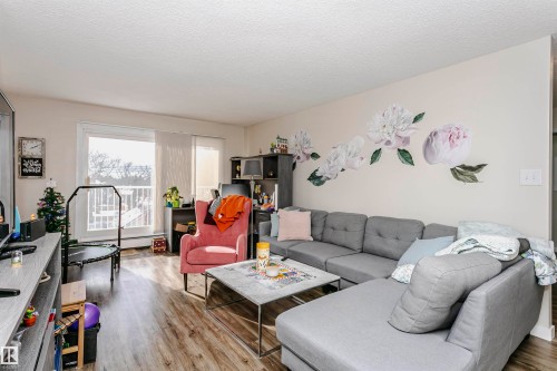 Living area with light wood-style floors and a textured ceiling - 407 8149 111 St S, Edmonton, AB - Indoor Photo Showing Living Room