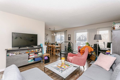 Living room featuring wood finished floors, a textured ceiling, and a chandelier - 407 8149 111 St S, Edmonton, AB - Indoor Photo Showing Living Room