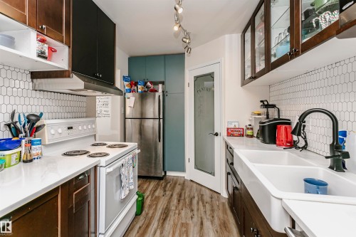 Kitchen featuring decorative backsplash, white electric stove, glass insert cabinets, freestanding refrigerator, and light wood-style flooring - 407 8149 111 St S, Edmonton, AB - Indoor Photo Showing Kitchen With Double Sink