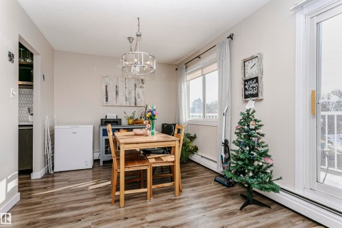 Dining area with baseboard heating, wood finished floors, and a chandelier - 407 8149 111 St S, Edmonton, AB - Indoor Photo Showing Dining Room