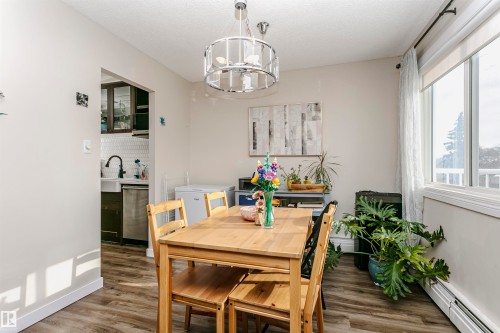 Dining area with dark wood finished floors, hanging lights, and baseboard heating - 407 8149 111 St S, Edmonton, AB - Indoor Photo Showing Dining Room