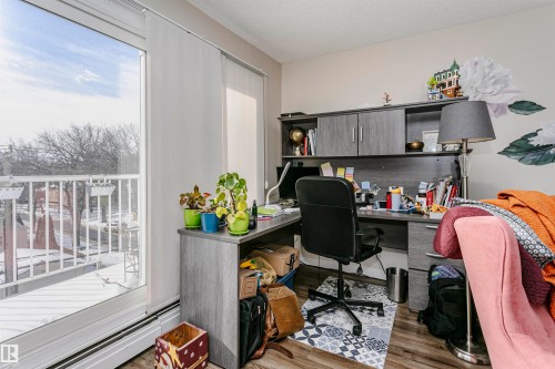 Office area featuring light wood-type flooring, a baseboard heating unit, and a textured ceiling - 407 8149 111 St S, Edmonton, AB - Indoor Photo Showing Office