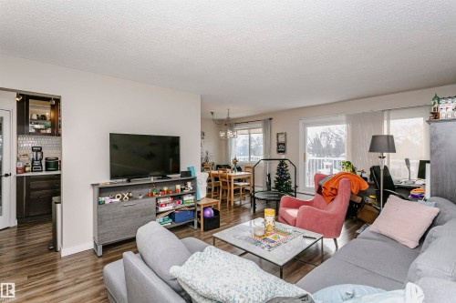 Living area featuring wood finished floors, a textured ceiling, and a chandelier - 407 8149 111 St S, Edmonton, AB - Indoor Photo Showing Living Room