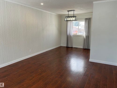Empty room with a textured ceiling, crown molding, and dark wood finished floors - 10832 163 Street, Edmonton, AB - Indoor Photo Showing Other Room