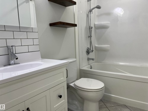 Bathroom with tasteful backsplash, vanity, washtub / shower combination, and light tile patterned floors - 10832 163 Street, Edmonton, AB - Indoor Photo Showing Bathroom
