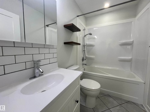 Bathroom with backsplash, vanity, shower / washtub combination, and light tile patterned floors - 10832 163 Street, Edmonton, AB - Indoor Photo Showing Bathroom