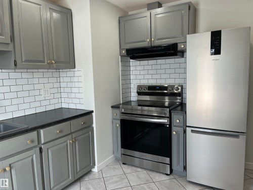 Kitchen with gray cabinetry, freestanding refrigerator, electric stove, backsplash, and light tile patterned flooring - 10832 163 Street, Edmonton, AB - Indoor Photo Showing Kitchen