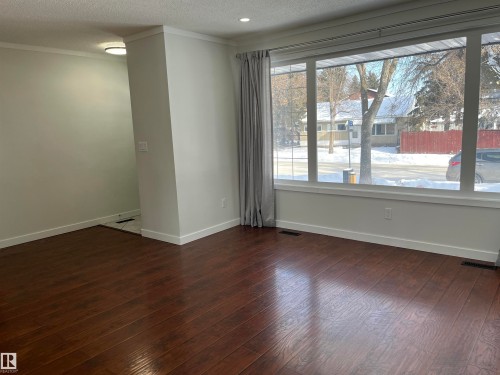 Unfurnished room featuring a textured ceiling, dark wood-type flooring, and crown molding - 10832 163 Street, Edmonton, AB - Indoor Photo Showing Other Room