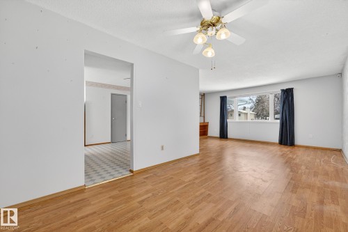 Empty room featuring light wood finished floors, a textured ceiling, and a ceiling fan - 21 Marchand Place, St. Albert, AB - Indoor
