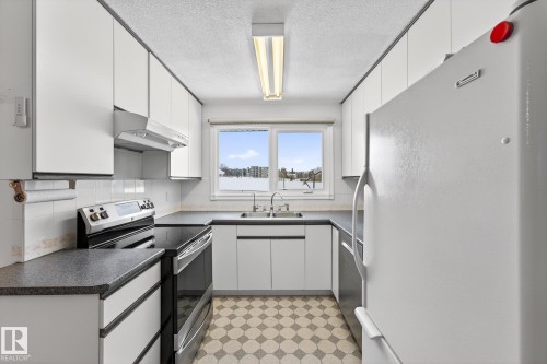 Kitchen featuring stainless steel appliances, dark countertops, a textured ceiling, and white cabinets - 21 Marchand Place, St. Albert, AB - Indoor Photo Showing Kitchen With Double Sink