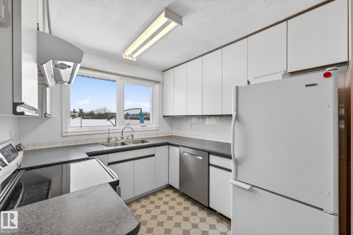 Kitchen with stainless steel appliances, dark countertops, light floors, white cabinets, and exhaust hood - 21 Marchand Place, St. Albert, AB - Indoor Photo Showing Kitchen With Double Sink