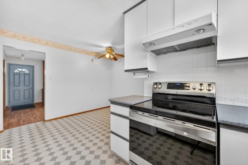 Kitchen featuring stainless steel range with electric cooktop, extractor fan, white cabinetry, light flooring, and ceiling fan - 21 Marchand Place, St. Albert, AB - Indoor Photo Showing Kitchen