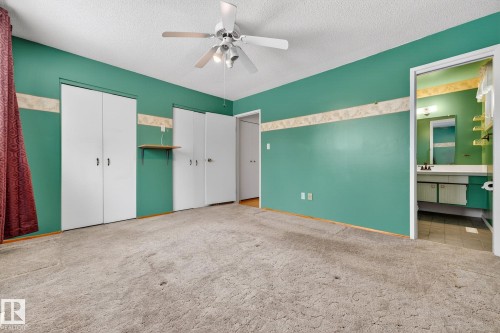 Unfurnished bedroom with two closets, light carpet, ceiling fan, a textured ceiling, and connected bathroom - 21 Marchand Place, St. Albert, AB - Indoor