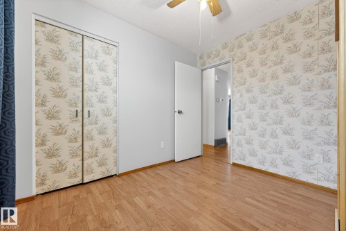 Unfurnished bedroom featuring a textured ceiling, light wood finished floors, ceiling fan, and wallpapered walls - 21 Marchand Place, St. Albert, AB - Indoor Photo Showing Other Room