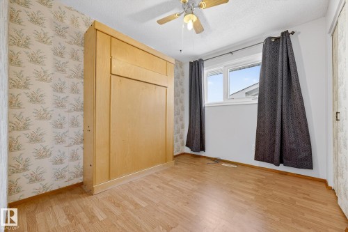 Unfurnished bedroom featuring light wood finished floors, ceiling fan, a textured ceiling, and wallpapered walls - 21 Marchand Place, St. Albert, AB - Indoor Photo Showing Other Room