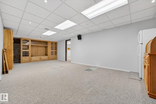 Finished below grade area featuring freestanding refrigerator, light colored carpet, and a paneled ceiling - 21 Marchand Place, St. Albert, AB - Indoor