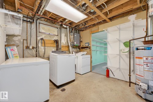 Laundry area featuring unfinished concrete floors, water heater, electric panel, and washing machine and clothes dryer - 21 Marchand Place, St. Albert, AB - Indoor Photo Showing Laundry Room