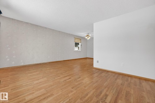 Unfurnished room featuring a textured ceiling, light wood-style floors, wallpapered walls, and a ceiling fan - 21 Marchand Place, St. Albert, AB - Indoor Photo Showing Other Room