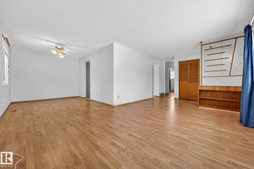 Unfurnished living room with light wood-type flooring, a textured ceiling, and a ceiling fan - 21 Marchand Place, St. Albert, AB - Indoor Photo Showing Other Room