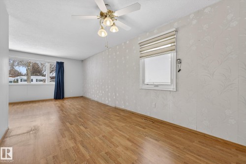 Unfurnished room featuring light wood finished floors, wallpapered walls, a textured ceiling, a ceiling fan, and plenty of natural light - 21 Marchand Place, St. Albert, AB - Indoor Photo Showing Other Room