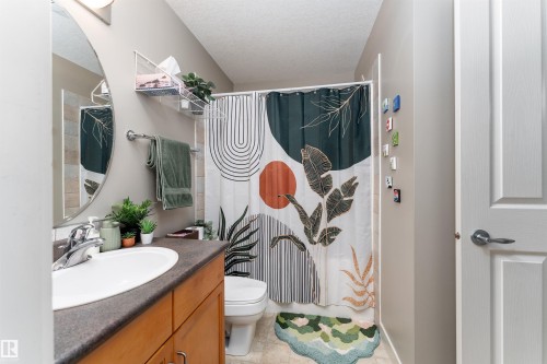 Full bath featuring vanity, curtained shower, a textured ceiling, and light tile patterned floors - 10906 72 Avenue, Edmonton, AB - Indoor Photo Showing Bathroom