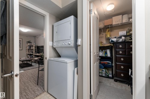 Laundry area featuring stacked washer / drying machine and light carpet - 10906 72 Avenue, Edmonton, AB - Indoor Photo Showing Laundry Room