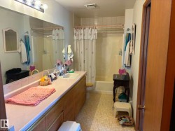 Full-length vanity mirror over a laminate countertop featuring an integrated sink, wood-finish cabinetry, and a full bathtub with a shower - 