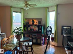 Room featuring a ceiling fan with integrated lighting, wood-finish flooring, and multiple windows with blinds - 