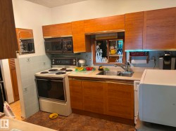 Kitchen featuring wood-finish cabinetry, a stainless steel double basin sink, and light blue tile backsplash - 