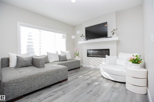 Living room featuring a glass covered fireplace and light wood finished floors - 15 Springbrook Wynd, Spruce Grove, AB - Indoor Photo Showing Living Room With Fireplace