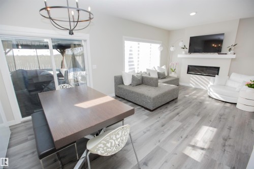Living room with suspended lighting, a glass covered fireplace, and wood finished floors - 15 Springbrook Wynd, Spruce Grove, AB - Indoor Photo Showing Living Room With Fireplace