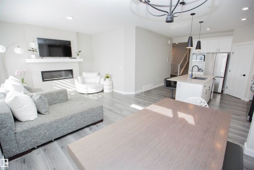 Living room with light wood-type flooring, a glass covered fireplace, and a chandelier - 15 Springbrook Wynd, Spruce Grove, AB - Indoor Photo Showing Living Room With Fireplace