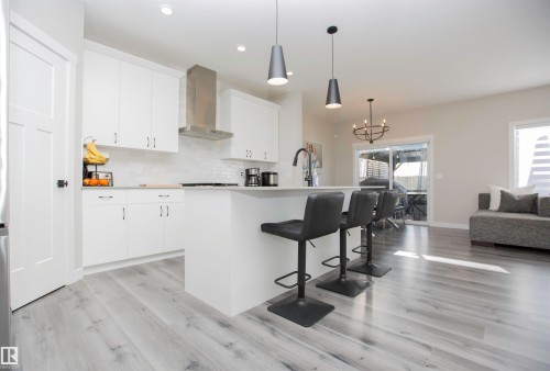 Kitchen with a breakfast bar area, an island with sink, white cabinets, and light countertops - 15 Springbrook Wynd, Spruce Grove, AB - Indoor Photo Showing Kitchen With Upgraded Kitchen