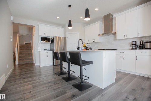 Kitchen featuring white cabinets, stainless steel appliances, light countertops, a center island with sink, and a breakfast bar area - 15 Springbrook Wynd, Spruce Grove, AB - Indoor Photo Showing Kitchen With Upgraded Kitchen