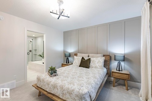 Bedroom with light carpet, a decorative wall, connected bathroom, and suspended lighting - 6275 180 Avenue, Edmonton, AB - Indoor Photo Showing Bedroom