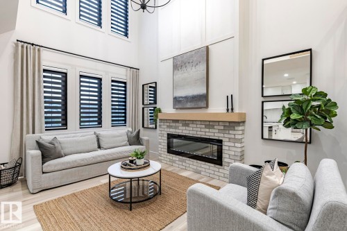 Living room with a brick fireplace, wood finished floors, and a high ceiling - 6275 180 Avenue, Edmonton, AB - Indoor Photo Showing Living Room With Fireplace