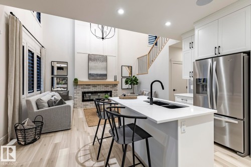 Kitchen with stainless steel fridge with ice dispenser, a kitchen island with sink, open floor plan, a kitchen bar, and white cabinetry - 6275 180 Avenue, Edmonton, AB - Indoor Photo Showing Kitchen With Double Sink With Upgraded Kitchen