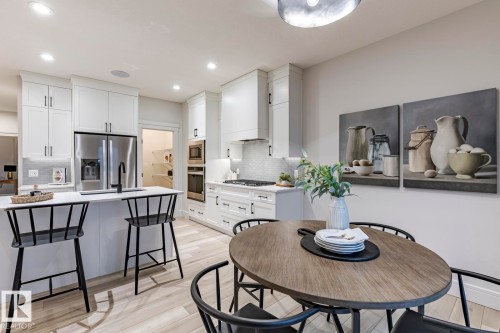 Kitchen featuring light wood-type flooring, a breakfast bar, white cabinetry, stainless steel appliances, and recessed lighting - 6275 180 Avenue, Edmonton, AB - Indoor