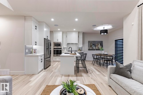 Kitchen with open floor plan, white cabinetry, an island with sink, a breakfast bar area, and recessed lighting - 6275 180 Avenue, Edmonton, AB - Indoor