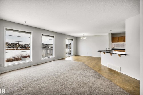 Unfurnished living room with suspended lighting and a textured ceiling - 3401 47 Street, Beaumont, AB - Indoor Photo Showing Other Room