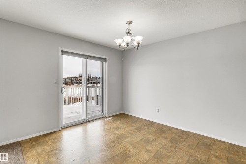 Empty room with hanging lights, stone finish floors, and a textured ceiling - 3401 47 Street, Beaumont, AB - Indoor Photo Showing Other Room