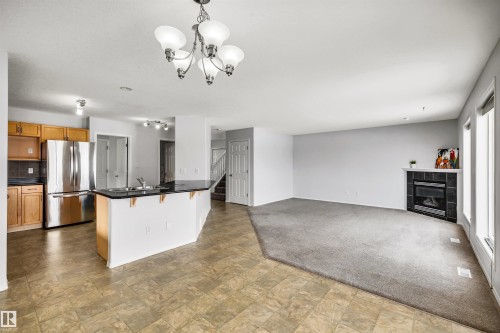 Kitchen with light colored carpet, stone finish floors, freestanding refrigerator, wood finish cabinets, and open floor plan - 3401 47 Street, Beaumont, AB - Indoor Photo Showing Other Room