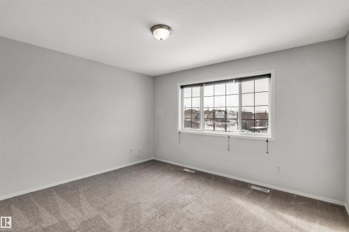 Carpeted empty room with baseboards and a textured ceiling - 3401 47 Street, Beaumont, AB - Indoor Photo Showing Other Room